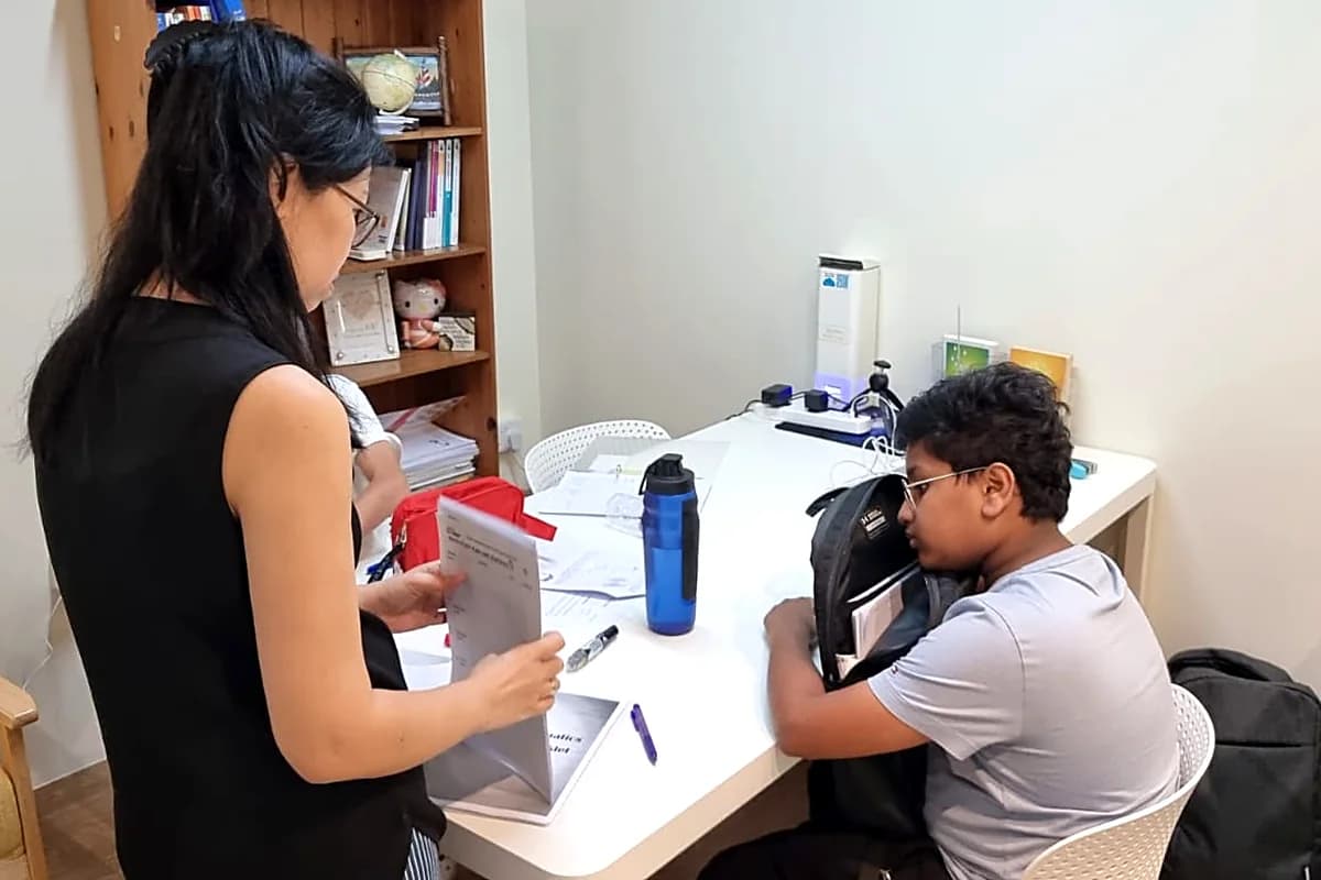 Teacher Elaine going through a marked maths paper with a student at the MathArchery studio.