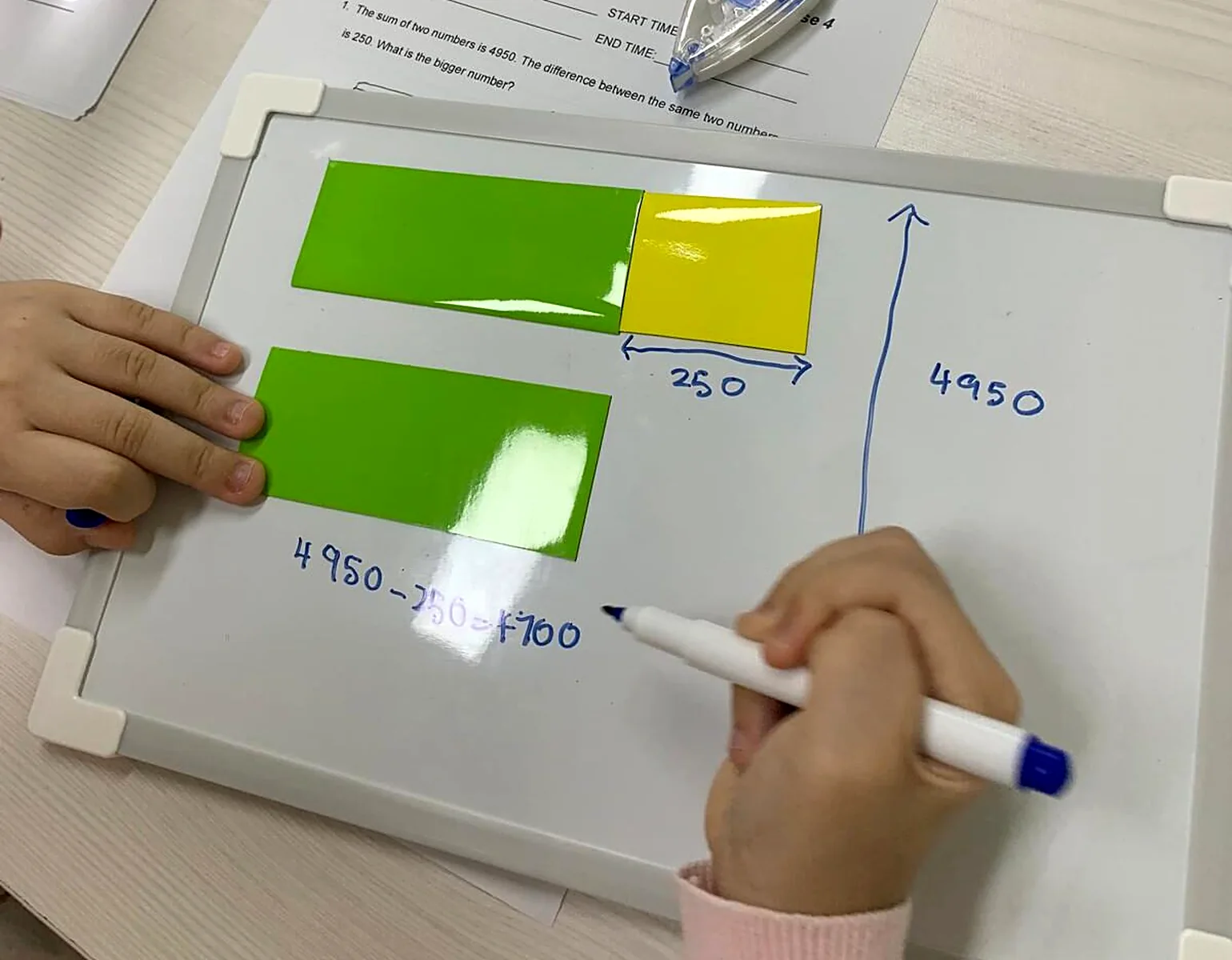 A student building a bar model with magnetic strips on a small whiteboard at the MathArchery studio.